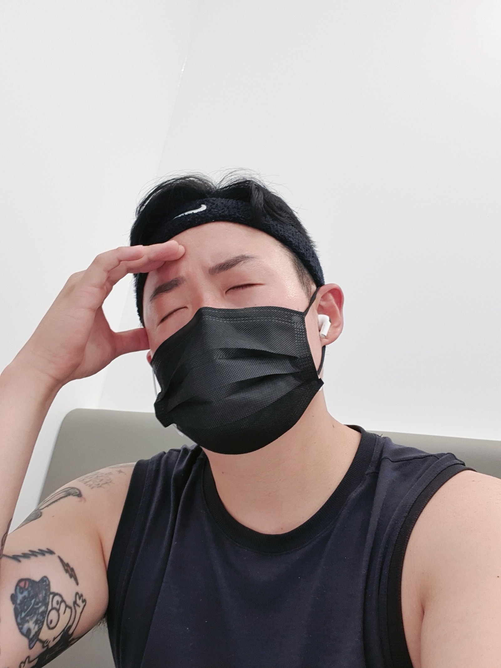 검은 마스크를 쓰고 이마를 짚은 채 눈을 감은 사진
