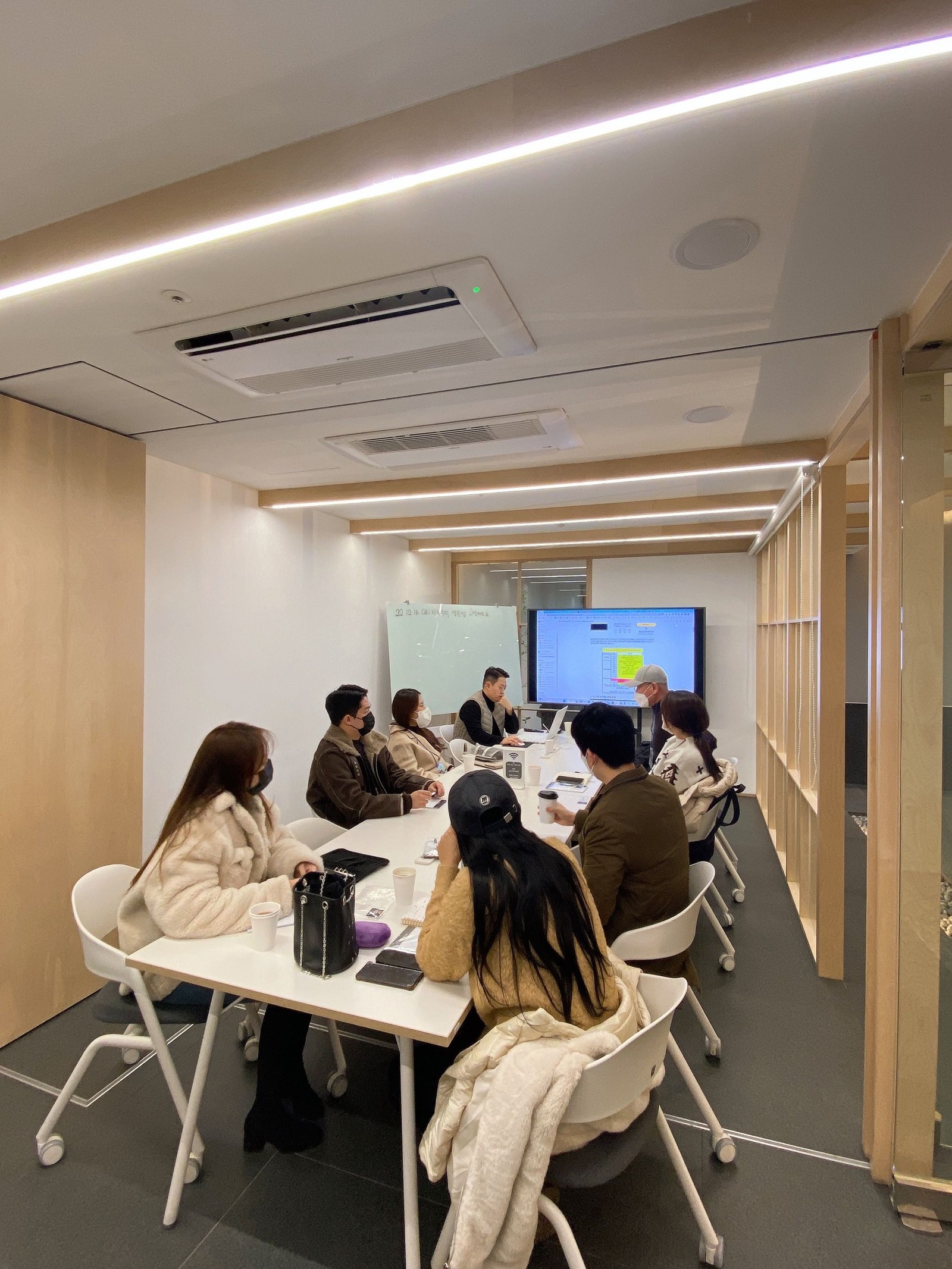 회의실에서 사람들이 테이블에 둘러앉아 강의를 듣는 모습